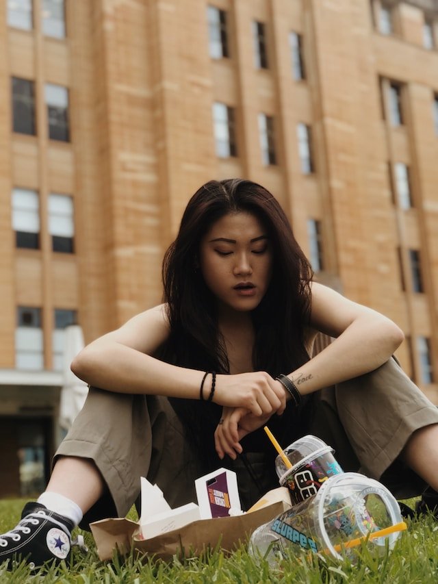 A woman regretting binging all the food in front of her.